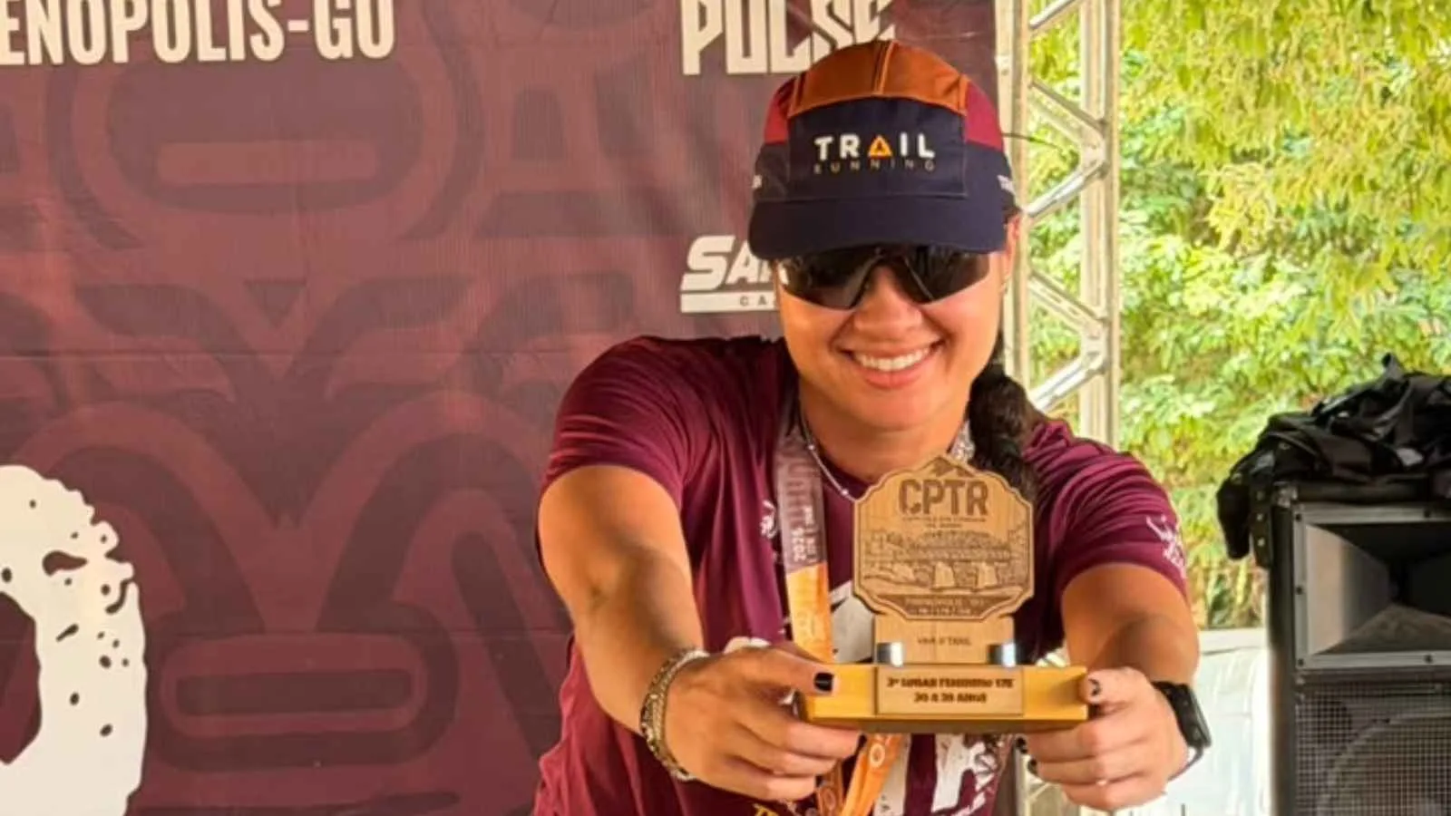 Carol Rodrigues, atleta de Jataí, segura o troféu de terceiro lugar em sua categoria por idade nos 17 km do Campeonato Goiano de Trail Running 2026, em Pirenópolis.